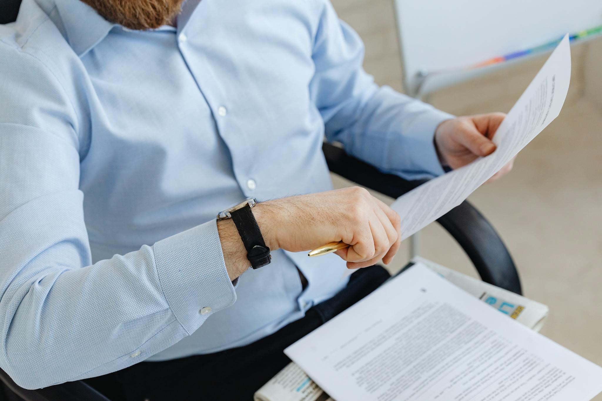 Businessman reviewing papers in office setting, highlighting analysis and attention to detail.